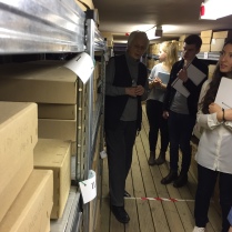Shows the students looking at the shelves of boxes in the museum stores